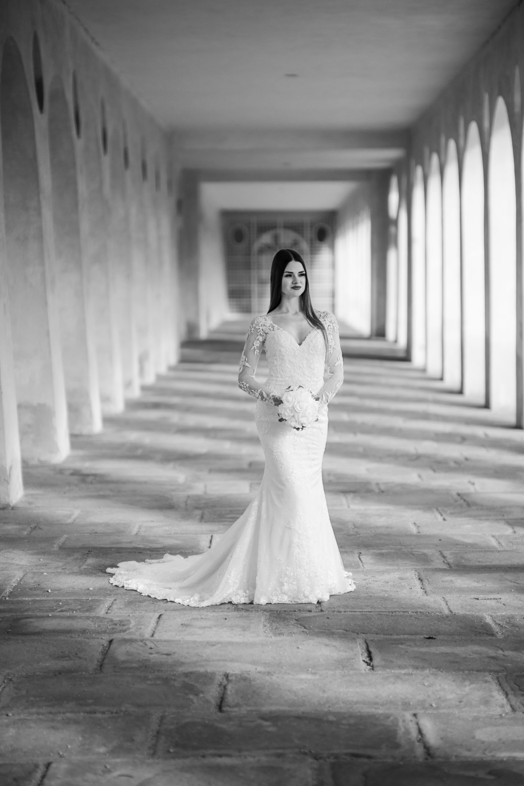 Braut steht alleine im Bogengang einer Orangerie