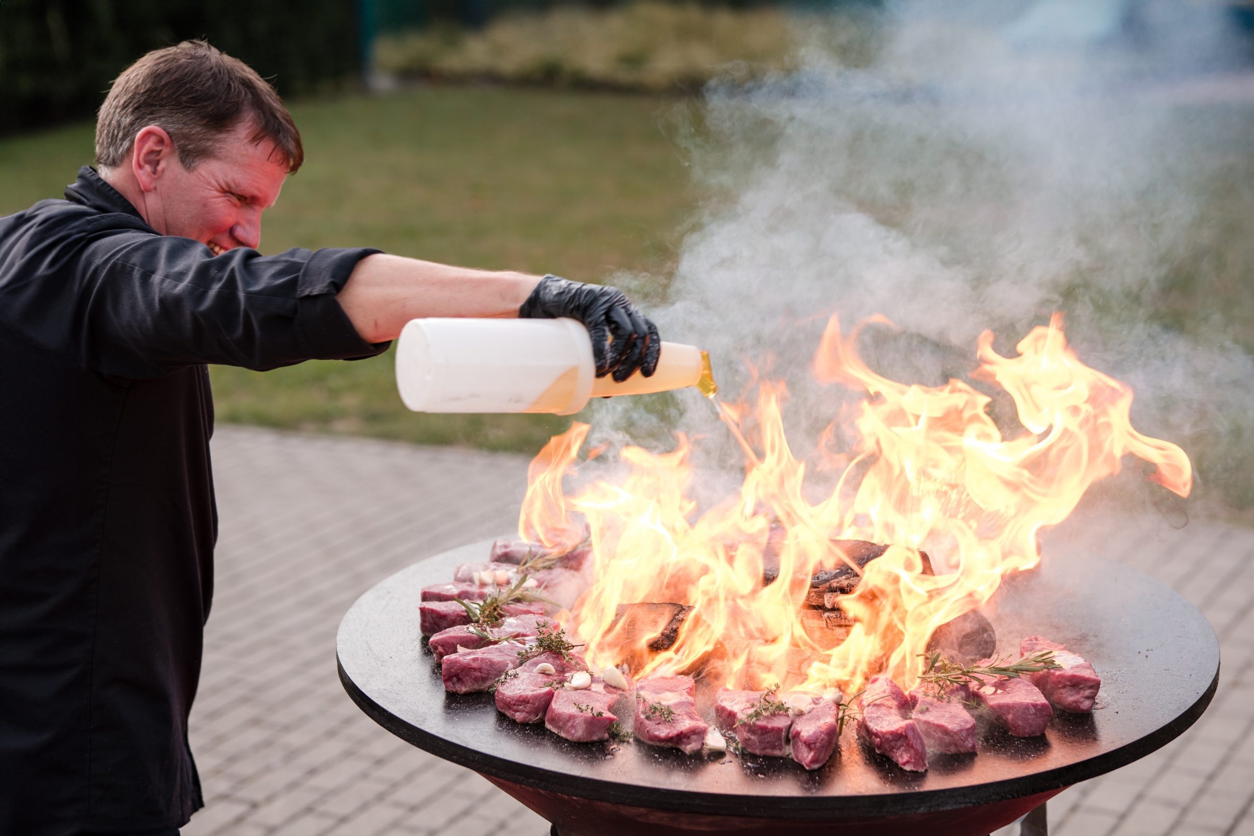 Der Koch Bernd Werner grillt Abendessenbei lodernden Flammen in der Eventlocaation Surumu