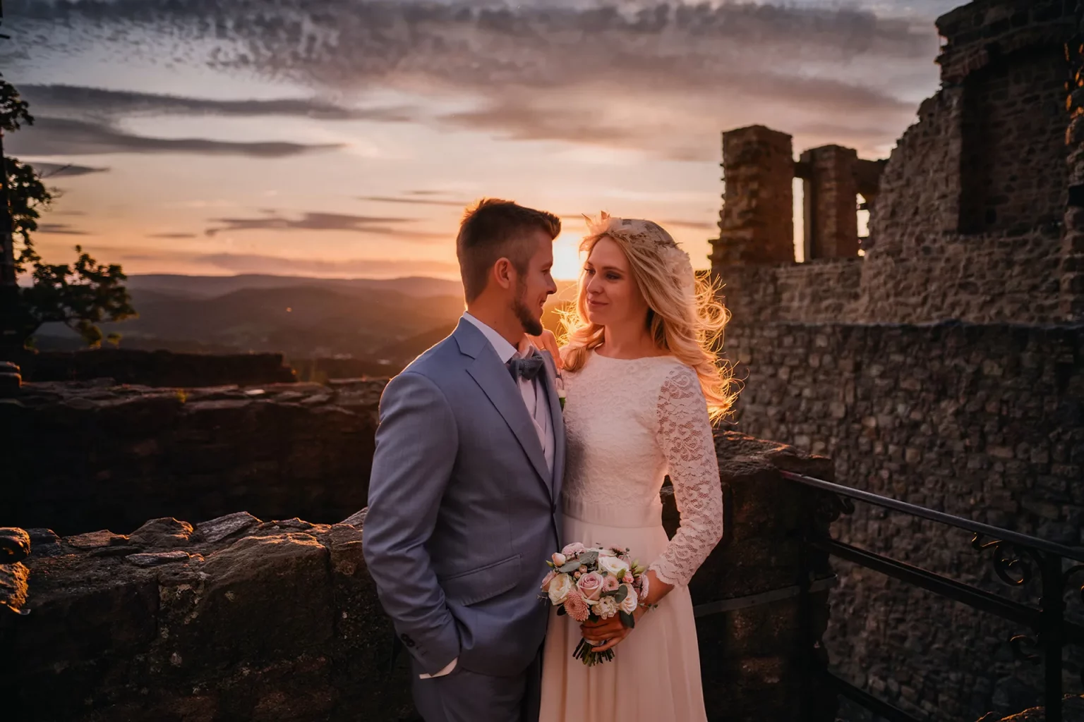 Hochzeitsfotografie in Baden-Baden: Brautpaat steht verliebt bei Sonnenuntergang bei der Ruine des alten Schloss bei Baden-Baden. Die Sonne leuchtet weich durch das Haar